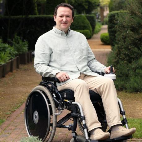 Ο σχεδιαστής τοπίου και ο παγκόσμιος παρουσιαστής των κηπουρών σηματοδοτούν τη λωρίδα σε αναπηρικό καροτσάκι στον κήπο του μουσείου geffrye