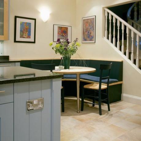 Γωνιακό καθιστικό συμποσίου στο τραπέζι σε μοντέρνα κουζίνα με γαλάζια μονάδα και σκάλα στον επάνω όροφο