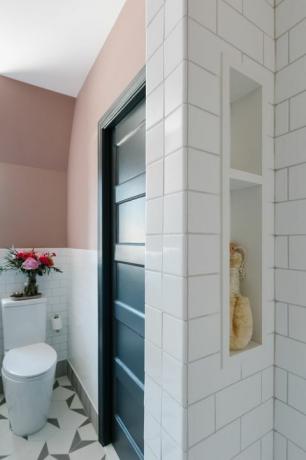 ροζ βαμμένος τοίχος, λευκό κεραμίδι μετρό, λευκή τουαλέτα, γεωμετρικά λευκά και γκρι πλακάκια, ενσωματωμένα σε ράφια