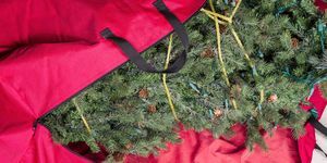 μεγάλο τεχνητό χριστουγεννιάτικο δέντρο που τοποθετείται σε κόκκινη νάιλον τσάντα με φερμουάρ