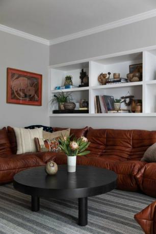 πορτοκαλί καναπές, μαύρο ξύλινο τραπεζάκι σαλονιού, χαλί απογυμνωμένο