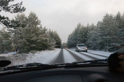 Ένα αυτοκίνητο οδηγεί στο δρόμο που καλύπτεται από χιόνι ανάμεσα στα δέντρα