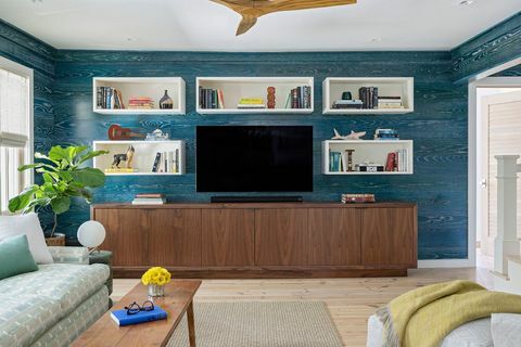 σαλόνι, μπλε επένδυση τοίχου, μπλε ταπετσαρία, κονσόλα πολυμέσων με τηλεόραση HD καθισμένη στην κορυφή, ξύλινος ανεμιστήρας οροφής, λευκές μικρές τρύπες