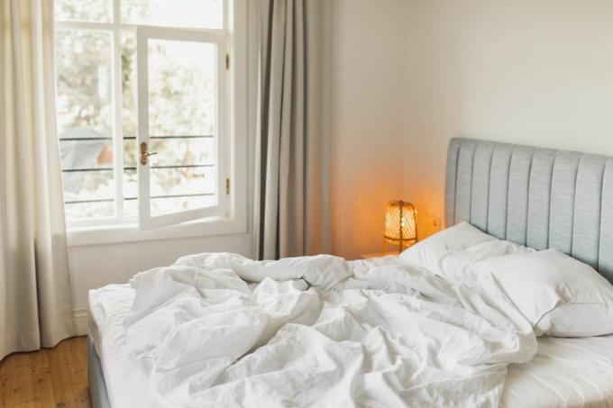 κρεβάτι σε δωμάτιο ξενοδοχείου με τσαλακωμένη κουβέρτα αφύπνιση έννοια ταξίδια και διακοπές