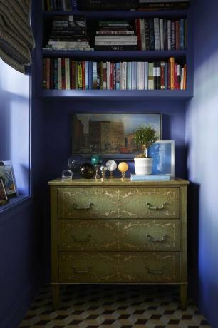 μπλε βαμμένοι τοίχοι, πράσινη συρταριέρα, μαρμάρινες μπάλες, διακοσμητικά βιβλία, λευκή γλάστρα
