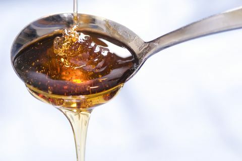 Ένα ψιλόβροχο σιρόπι ή μέλι πέφτει μέσα και έξω από ένα κουτάλι.