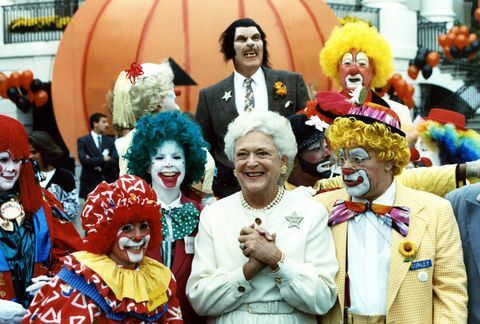 αυτή η φωτογραφία είναι της πρώτης κυρίας Μπάρμπαρα Μπους που χαμογελάει καθώς ποζάρει με καλλιτέχνες, μια ομάδα κλόουν και ένας μοναχικός λυκάνθρωπος στη νότια αυλή του λευκού οίκου ως μέρος του Halloween εορτασμός